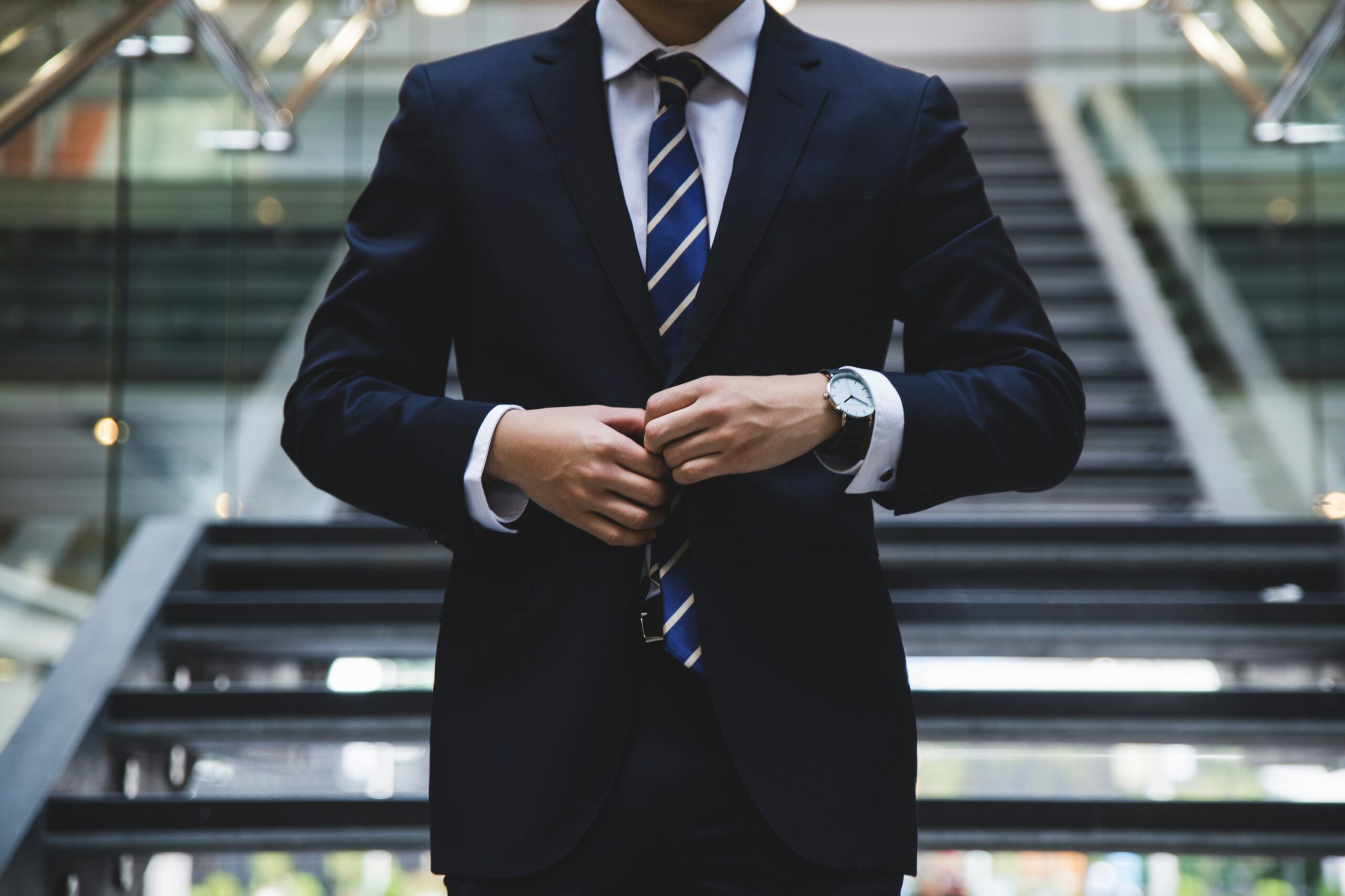 Man descending stairs in suit, adjusting tie