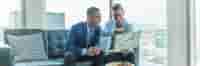 Two men in suits looking over laptop