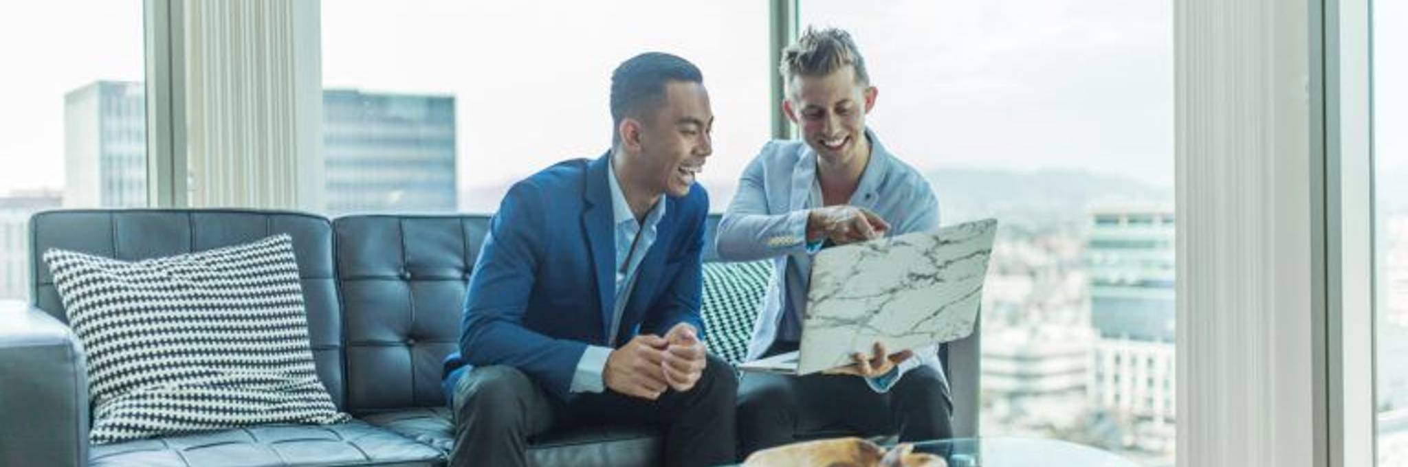 Two men in suits looking over laptop
