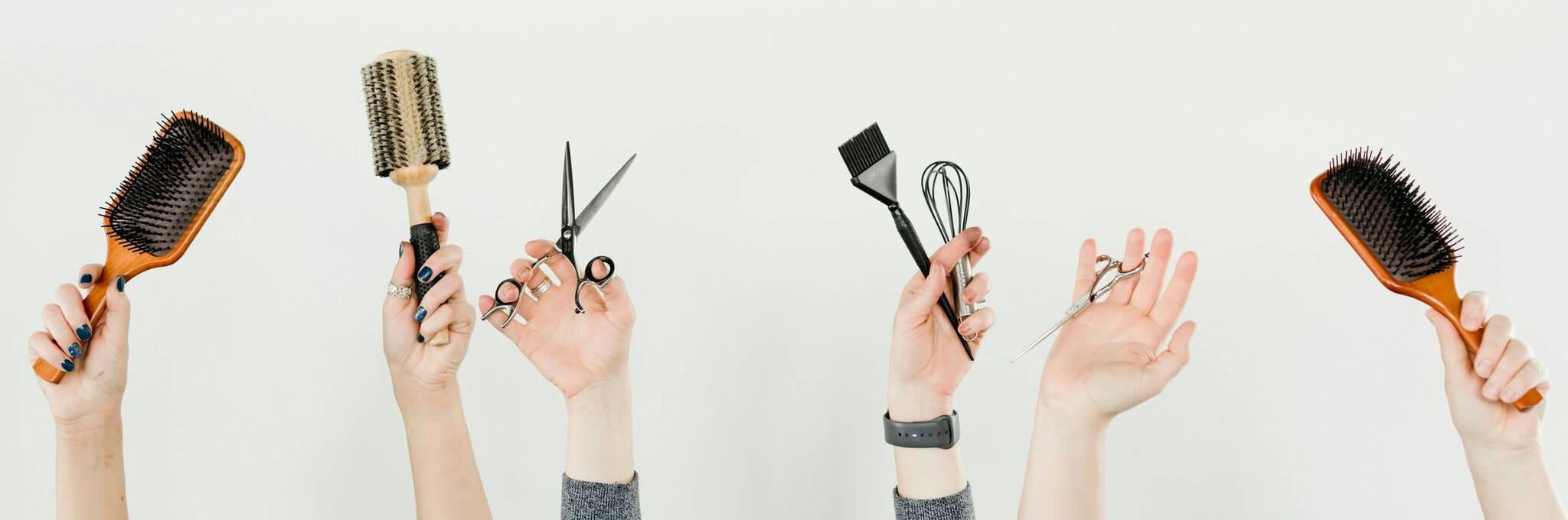 multiple hands holding brushes and scissors